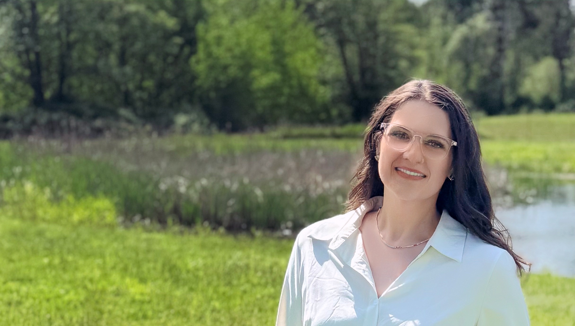 Jessica Rienstra, candidate for Whatcom County Council District 3, standing in a meadow with water and trees in the background
